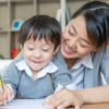 young mother teaching her son write paper with love